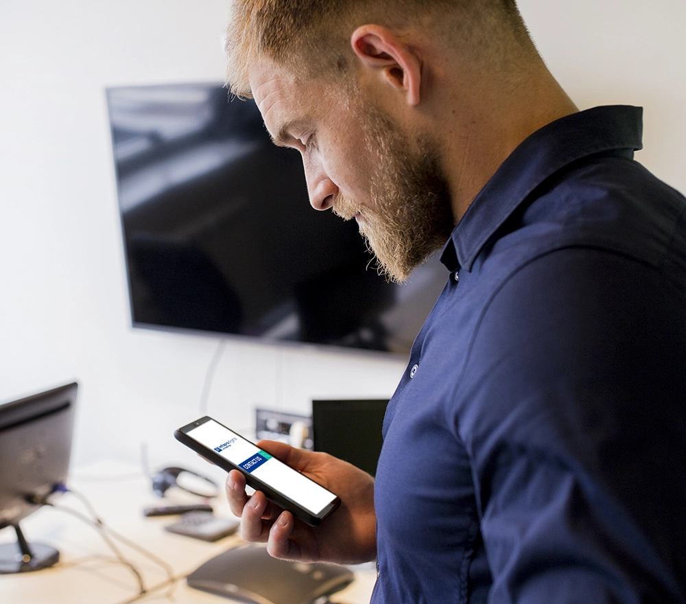 Uomo con telefono portatile che sta per contattare Infopro Digital Automotive
