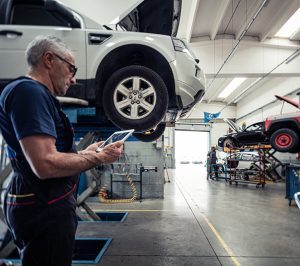 Mécanicien automobile en atelier consultant des données techniques et des méthodes de réparation sur une tablette grâce aux logiciels Infopro Digital Automotive