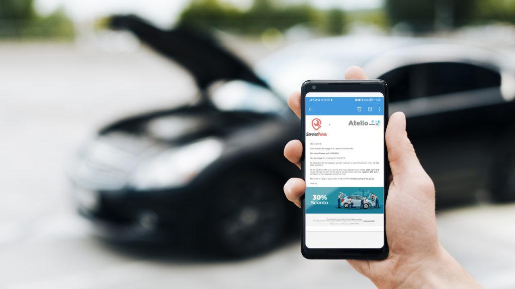 Hand holds a mobile phone showing an email received thanks to atelio fid workshop marketing software