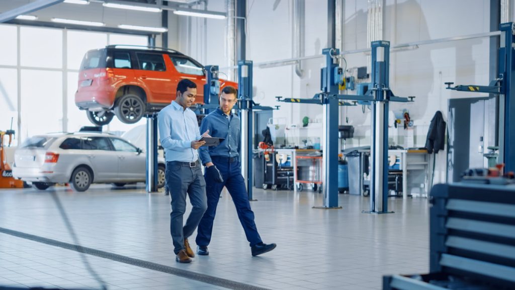 Professionisti della riparazione auto in officina mentre usano i software su misura per OEM, officine e distributori di Infopro Digital Automotive