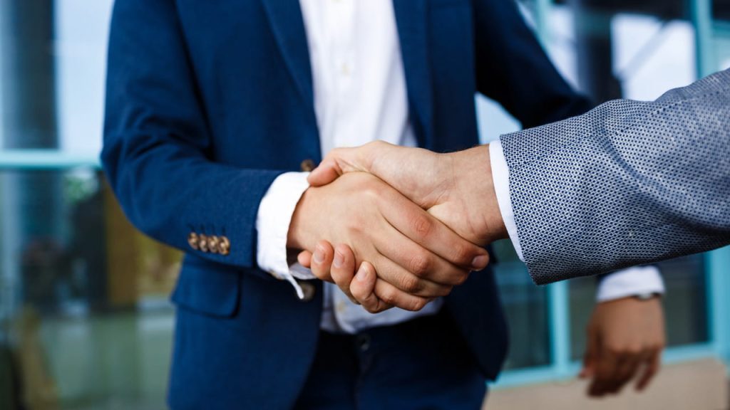 Due uomini si stringono la mano dopo aver firmato un contratto d'affari