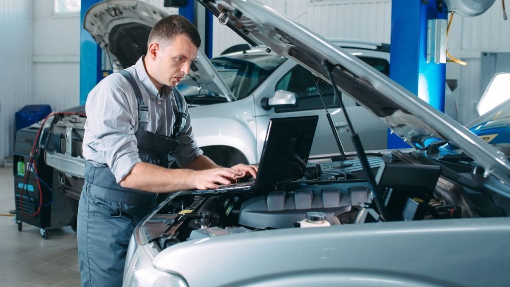 Meccanico al lavoro su un veicolo in officina che utilizza dati e software di Infopro per Officine e centri Fast Fitt