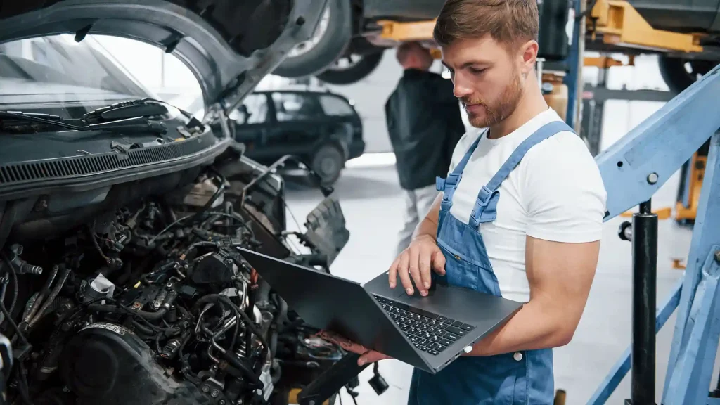 Meccanico auto in officina che ha appena ricevuto via email la documentazione tecnica per l’autoriparazione a richiesta