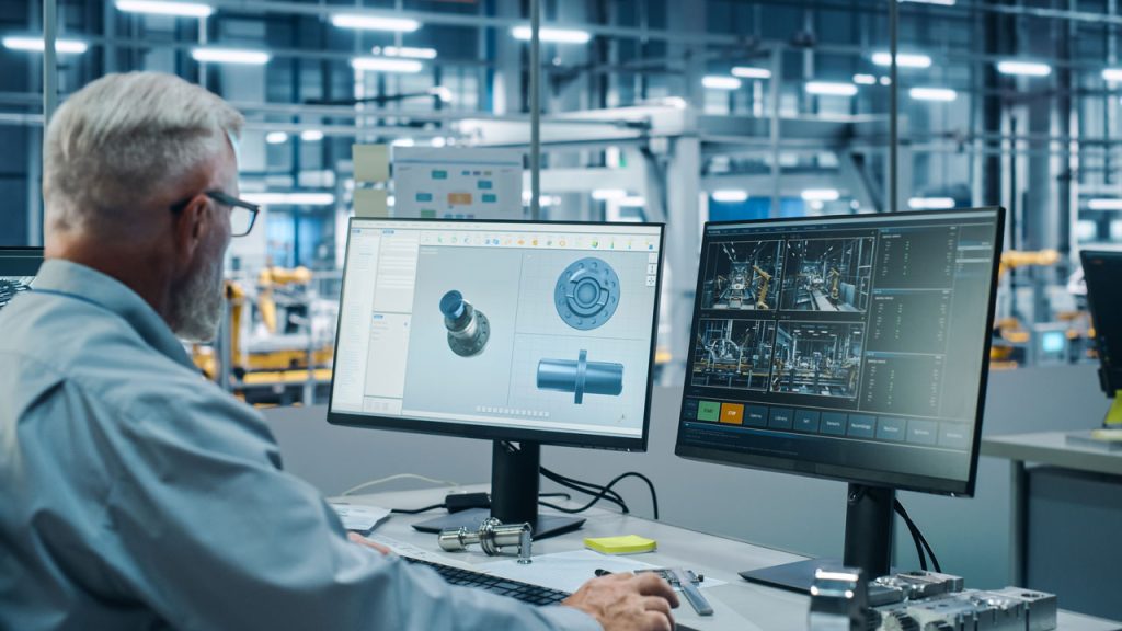 Ingegnere che progetta parti di automobili al computer all'interno di uno stabilimento di produttori di ricambi e di strumenti di diagnosi