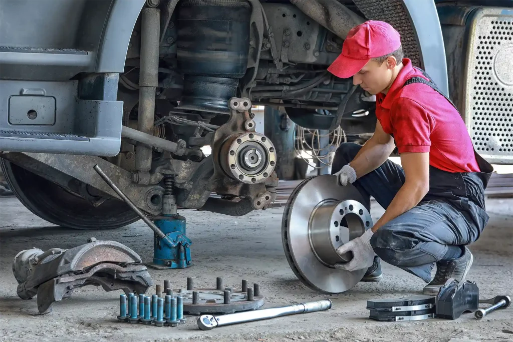 Mécanicien remplaçant une pièce sur un poids lourd grâce à une commande sur Atelio Parts Truck