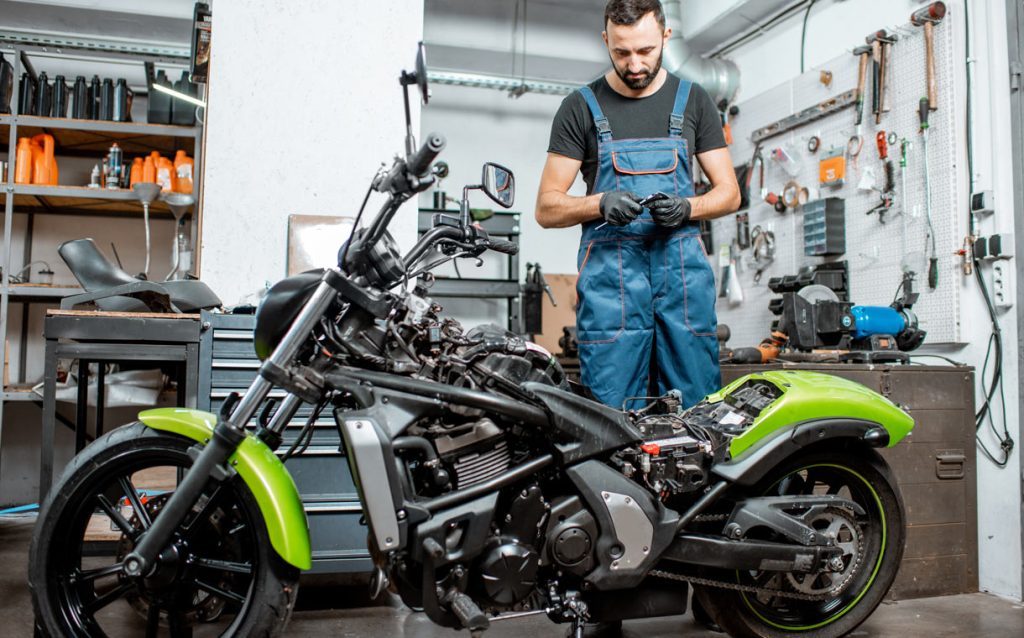 Mechanic repairing a motorbike in the workshop using Atelio Data Moto