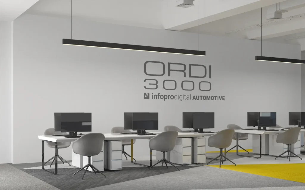 Photo des bureaux d'ORDI3000 à Tarbes avec des bureaux, des chaises, des ordinateurs et le logo ORDI3000/Infopro Digital Automotive sur le mur du fond