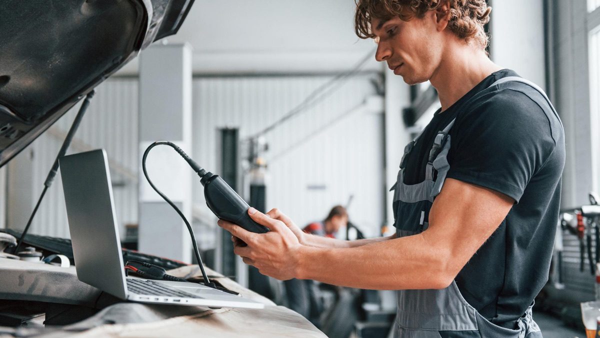 Technician using diagnostic testing equipment to repair an electric vehicle in a workshop