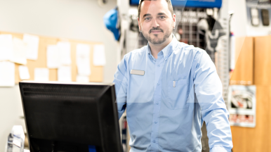 Employé dans le bureau d'un garage automobile consulte le planning atelier sur son ordinateur