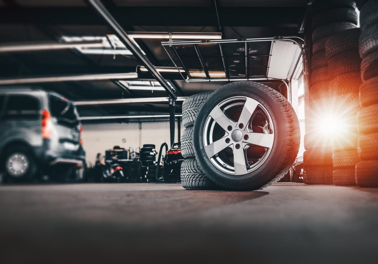 Fast Fit garage with stacked tires and a wheel in the foreground, representing comprehensive ERP and DMS solutions for the automotive aftermarket industry