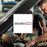 Two mechanics working under the bonnet of a vehicle while consulting Atelio Data on the computer leaning against the engine
