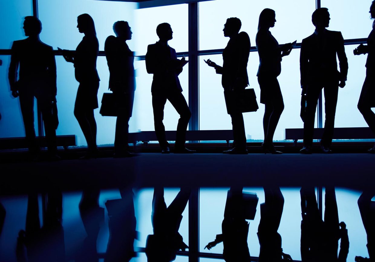 Business professionals discussing in a glass meeting room, symbolizing Infopro Digital Automotive's expertise in automotive data and software