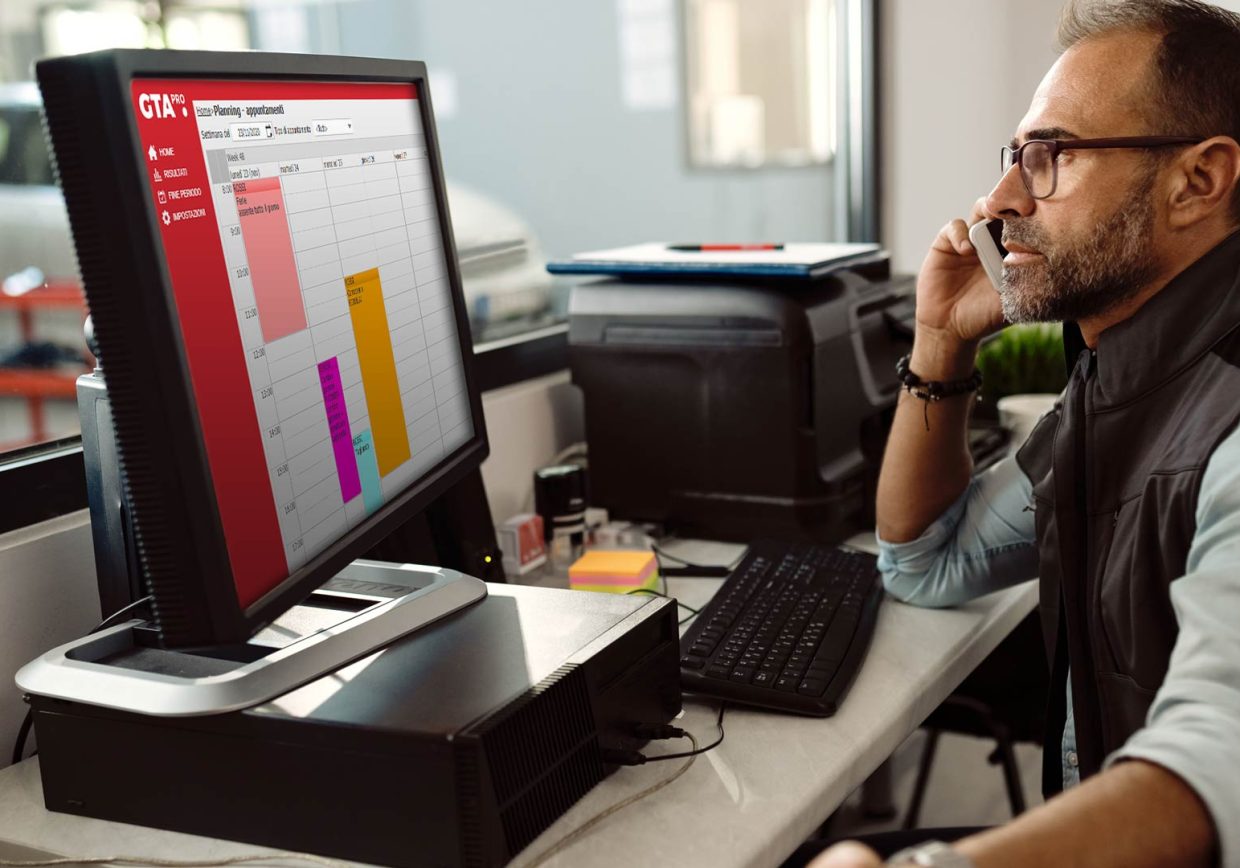 Rèparateur auto au bureau, organisant le travail de l'atelier à l'aide du système de gestion Gta Pro.