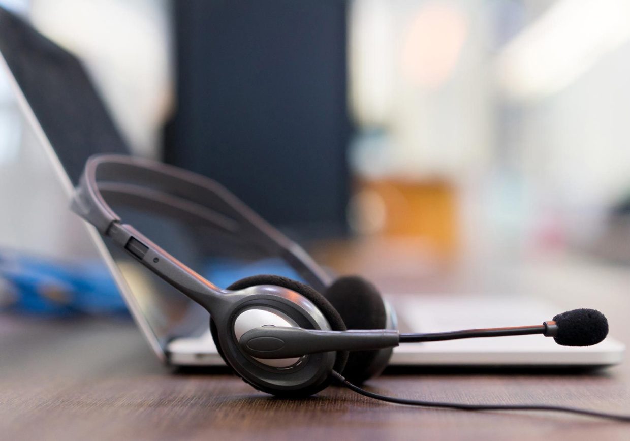 Casque avec micro posé sur un bureau avec un ordinateur en arrière-plan utilisé par un formateur Infopro Digital Automotive