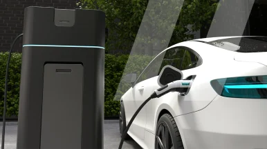 Un'auto elettrica bianca collegata a una stazione di ricarica, che rappresenta l'impatto di Infopro Digital Automotive sulla manutenzione dei veicoli elettrici e ibridi nell'aftermarket globale.