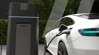 Une voiture électrique blanche connectée à une borne de recharge, représentant l'impact d'Infopro Digital Automotive sur la réparation des véhicules électriques et hybrides sur le marché mondial de l'après-vente.