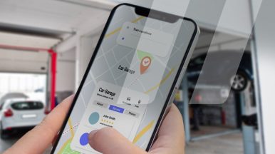 Personne tenant son téléphone afin de trouver un garage ou un vendeur de pièces automobiles proche de là où il se trouve