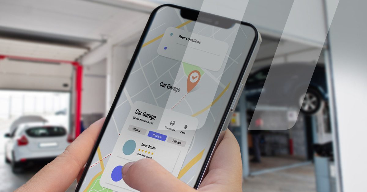 Personne tenant son téléphone afin de trouver un garage ou un vendeur de pièces automobiles proche de là où il se trouve