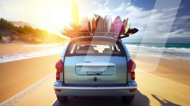 Coche circulando por la playa con maletas y tablas de surf colgando del techo