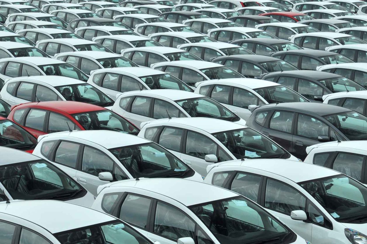 Image of many white and some red cars representing the car parc in circulation
