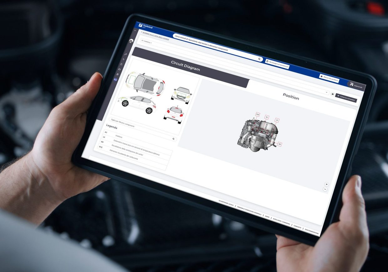 Hands of an auto mechanic using a tablet to access OEM repair information and vehicle technical data with Technical Data software in a U.S. repair workshop.