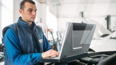 Auto technician in a U.S. workshop using OEM technical data on a computer to diagnose and repair a European vehicle such as BMW or Mercedes-Benz.