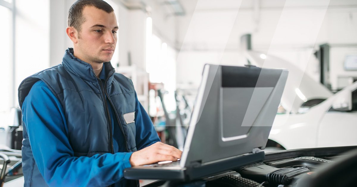 Auto technician in a U.S. workshop using OEM technical data on a computer to diagnose and repair a European vehicle such as BMW or Mercedes-Benz.